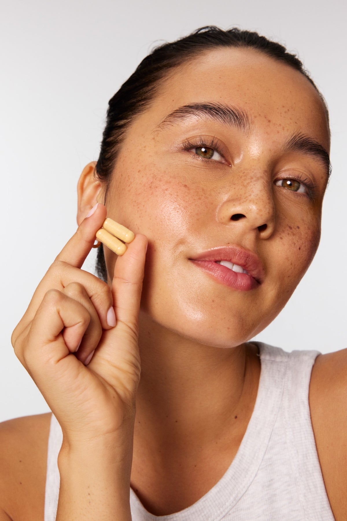 Woman holding MINDBODYSKIN® capsules to her cheek